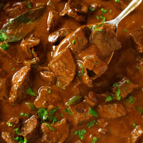 A spoon being used to dip a scoop out of a pan of Carne Guisada. The mixture is dark brown with flecks of bring green cilantro. Steak Burritos, Guisada Recipe, Carne Guisada, Layered Salad, Mexican Spices, Cooking White Rice, Sirloin Steaks, Meat And Cheese, Mexican Dishes