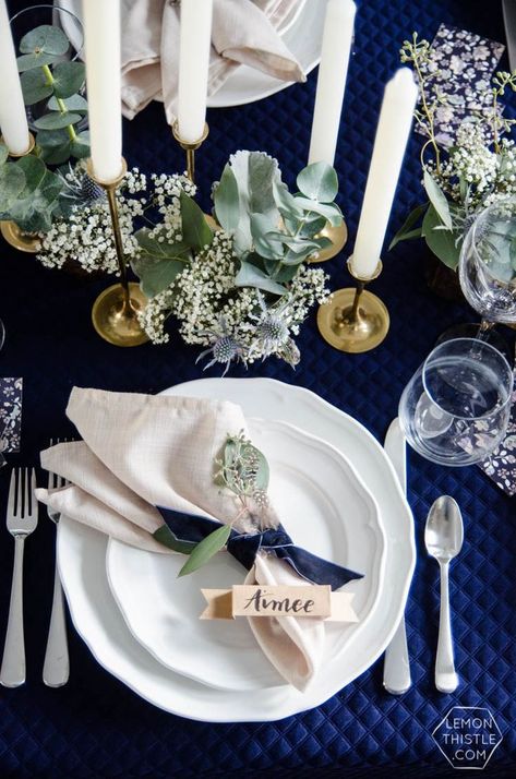 Napkins tied with velvet ribbon in pretty navy and white tablescape with white plates, gold candlestick holders, and leafy greens - Napkin idea Navy Blue And White Centerpieces, Navy Tablecloth, Dinner Party Tablescapes, Wedding Coral, Dinner Party Table Settings, Table Plate, Wedding Navy, Dinner Party Decorations, Blue Christmas Decor