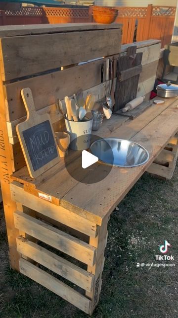 The Vintage Spoon | Mackenzie Winterton on Instagram: "DIY Pallet Mud Kitchen!  So excited about this mud kitchen! We still need to add a shelf on the bottom but the  kids absolutely love it! They are always making mud pies and potions in the summer so i wanted to make a space for them to do that and my husband help make that happen! The best part is its made out of mostly pallets and scrap wood from our deck build. I bought all the accessories at the thrift store and a couple things from the dollarstore. We are so ready for summer time over here!  #mudkitchen #montessori #letthembelittle #sahm#kids #simplejoys #momlife#yql #diy#momsofinstagram #pallet #palletprojects #diyprojects#palletmudkitchen #mudkitchen #mud" Mud Kitchen Made From Pallets, Mud Kitchen Out Of Pallets, Mud Kitchen Set Up Ideas, Mud Kitchen Accessories Ideas, How To Make A Mud Kitchen, Mud Kitchen For Kids Pallets, Mud Kitchen Pallets, Kids Mud Kitchen Diy, Pallet Mud Kitchen Diy