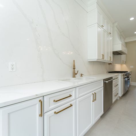 Full wall backsplashes are made to harmonize the countertops and backsplash with the entirety of the kitchen. Just look at that perfect symphony of whites and gentle marble-looking veining -- so elegant and beautiful! 🌿 

Contact us today for your quartz countertops + quartz backsplash combo. 🙌 

#howwedwell #kitchendesign #whitecabinets #kitchenmakeover #standoutstyling
#kitchenenvy #smmakelifebeautiful #thedelightofdecor #dailydecordose #whiteandgold #customkitchen #quartzbacksplash Solid Marble Backsplash Kitchen, Kitchens With Marble Backsplash, Backsplash Kitchen Quartz, White Marble Backsplash Kitchen, Backsplash With Quartz Countertop, Full Wall Backsplash, White Marble Kitchen Backsplash, Kitchen Quartz Backsplash, Quartz Backsplash Kitchen