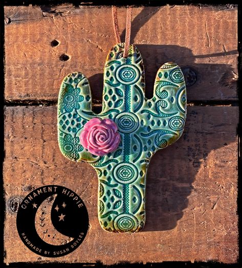 Handmade Ceramic Ornament by Susan Boyles Handmade, ceramic clay cactus ornament with a lace pattern and a pink rose! These ornaments make wonderful gifts throughout the year! Glazed and fired in a beautiful turquoise color with hints of rustic green around the edges. Ornament measures 4" tall x 3" wide. Ornament comes with an attached leather cord for hanging. Because every ornament is handmade; shape, color, flower placement pattern and size will vary slightly. All orders are shipped via USPS First Class Mail with tracking info. Please allow up to 2 weeks for delivery of your order. Desert Ornaments, Pottery Cactus, Clay Cactus, Handbuilt Pottery, Arizona Decor, Cactus Ceramic, Pottery Ornaments, Marble Falls, Clay Clay