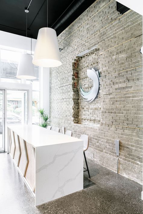 Hella Design Studio | Calgary Interior Design The reception desk got a major refresh. A waterfall quartz countertop, ample seating, and exposed brick feature wall are all a part of a warm welcome! 📷: @heymjay Brick Feature Wall, Gold Light Fixture, Massage Clinic, Light Brick, Entry Lighting, Counter Design, Custom Vanity, Reception Area, Reception Desk