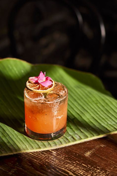 Upon a tropical leaf sits a bright peach coloured drink in a short glass. Ice accompanies the liquid, as a dried lime slice and pink flower adorn the top. Captured at Rice Paper Scissors in Melbourne. Image belongs to Instant Crush Creative. Dried Lime, Orange Drink, Lime Slice, Short Glass, Orange Drinks, Cocktail Photography, Leaf Photography, Colorful Cocktails, Tumbler Glass