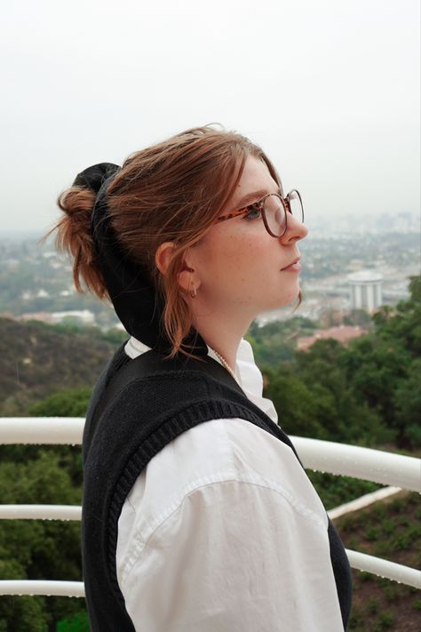 Young woman with glasses looks into the distance over the LA city skyline wearing a sweater vest and a white button down shirt. Blonde art student aesthetic Sony Zv-e10 Photography, Woman In Glasses, The Getty Center, Getty Center, Art Student, Aesthetic Outfit, Womens Glasses, City Skyline, Student Art