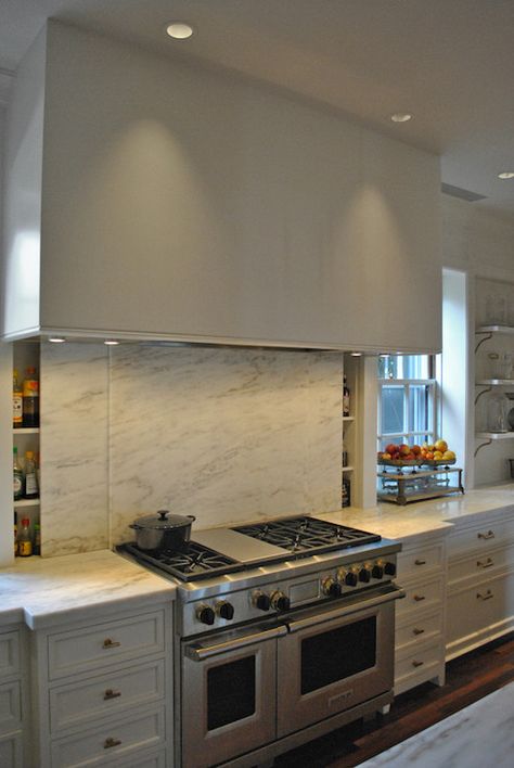 Innovative kitchen with stainless steel stove pairing with large range hood over sliding marble slab backsplash concealing slim spice rack. Backsplash Herringbone, Hidden Pantry, Kitchen Innovation, Stainless Steel Stove, White Kitchen Backsplash, Kitchen New York, Beadboard Backsplash, Custom Kitchens Design, Hidden Kitchen