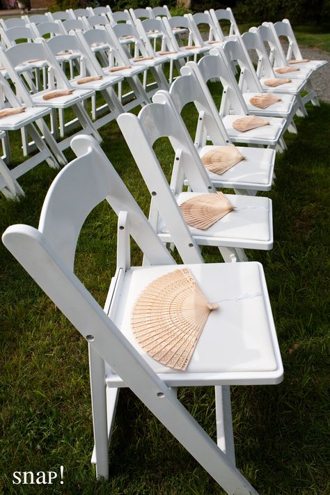 Ceremony fans for summer weddings Paper Fans Wedding Outdoor Ceremony, Fans On Seats Wedding, Wedding Chair Set Up Ceremony Seating, Fans On Chairs Wedding, Beach Wedding Umbrellas, White Fans Wedding, Umbrellas At Wedding Ceremony, Fans At Wedding Ceremony, Outdoor Wedding Chair Decorations