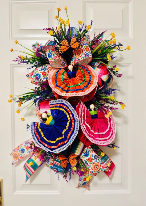 Celebrate Hispanic Heritage Month or 5 de Mayo with this one-of-a-kind, handcrafted swag! 🌸 This vibrant piece captures the essence of Mexican culture, featuring adorable folk dance dolls in traditional dresses, colorful ribbons, and bright floral accents that bring the fiesta to life. 🌼 Perfect for adding a pop of color to your front door, entryway, or wall, this swag is designed to be a celebration of culture, art, and joy. Every detail is carefully crafted to reflect the beauty and vibrancy of our heritage. *Handmade with high-quality materials *Features traditional folk dance dolls with intricate ribbon skirts *Bold floral accents, monarch butterflies, and colorful ribbons *Ideal for front door, home decor, or as a unique gift for any occasion *Dimensions: 18" x 32" x 8"   🎨 Whether Mexican Wreath Front Doors, Mexican Christmas Wreath, Mexican Decor Ideas, Mexican Wreath, Mexican Folk Art Decor, Mexican Party Favors, Mexican Christmas Decorations, Dia De Los Muertos Decorations Ideas, Mexican Traditions