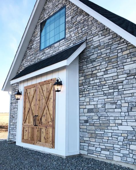 Happy Monday! Our new home has a four car sideload garage so the side of the garage is on the front portion of the home. We created these faux barn doors so that the front of the house had extra curb appeal and had the appearance of a stone barn. We have some landscaping planned for around this area as well so it is not finished but it is coming along!🌱 •Cedar is stained with a clear poly •stone is @eldoradostone white bark •lights are @kichlerlighting •paint is @benjaminmoore Chantilly lace •w Shed Attached To House, Curb Appeal Garage, Exterior Lighting Ideas, Home Lighting Ideas, Girls Bedroom Lighting, Lean To Shed, Window Trim Exterior, Exterior Light Fixtures, Stone Barns