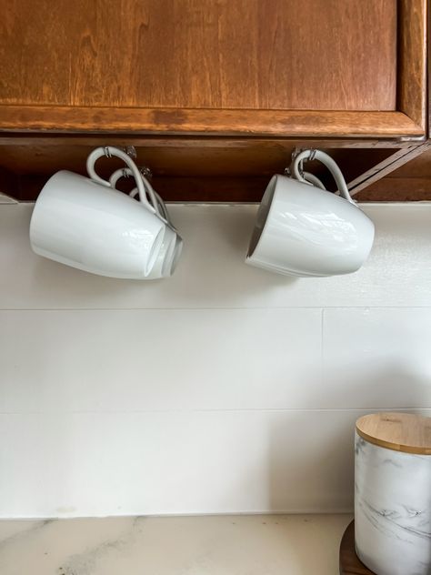 Easy Hack for Hanging Coffee Mugs Under a Cabinet - Smallish Home Hanging Cups Under Cabinet, Glasses And Mugs Organization, Hang Coffee Mugs Under Cabinet, Organizing Mugs In Cabinet, Under Shelf Hooks For Mugs, Under Cabinet Mug Hooks, Cup Hanger Ideas Kitchens, How To Hang Coffee Mugs, Hanging Coffee Mugs Under Cabinet