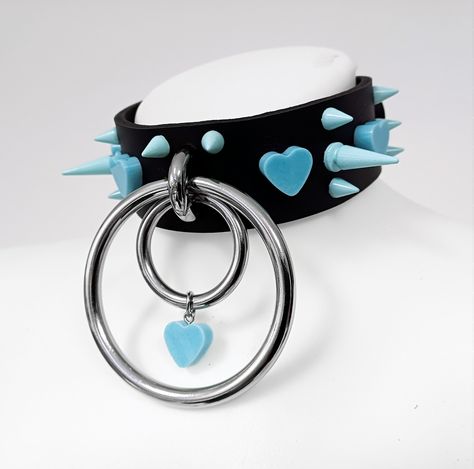 Stylish Pastel Goth Leather Choker: Material:  35mm wide genuine leather with baby blue spikes and handmade hearts. Spikes:  Stand out with 25mm and 10mm spikes for a unique edge. Closure:  Easy-to-wear roller buckle at the back of the neck. Rings:   70mm and 35mm in diameter rings add a trendy touch. Comfortable Fit:  Enjoy comfort and simplicity in every wear. - Perfect Accessory for Alternative Styles: Ideal for Kawaii and Pastel Goth enthusiasts. Elevate your style for parties, events, or daily looks. Styling Options: - Casual Chic: Pair it with a graphic tee and ripped jeans for an effortlessly cool vibe. - Edgy Elegance: Combine with a black dress and combat boots for a bold, yet sophisticated look. - Kawaii Cutie: Match with a pastel-colored skirt and crop top for a playful and cute Pastel Rock, Unique Accessories, Alternative Style Choker For Cosplay, Emo Choker For Alternative Fashion, Gothic Spiked Choker For Festivals, Gothic Heart-shaped Metal Choker, Pastel Goth Choker, Pastel Accessories, Neck Rings