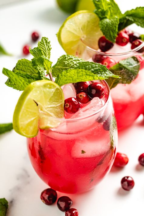 Our Cranberry Mojito combines tangy cranberry syrup, fresh mint, and white rum to create an unforgettable holiday cocktail! Serve a round to be merry and bright or enjoy this refreshing twist on the classic cocktail all year long! Pom Mocktail, Pomegranate Mojito, Cranberry Mocktail, Pomegranate Drinks, Gin Drink Recipes, Holiday Mocktail, Cranberry Pomegranate, Charcuterie Party, Vegan Drinks Recipes