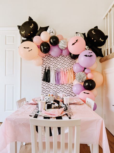 Break away from the traditional Halloween colors with this girly party set. The balloon bundle includes peach, pink, and purple girly-colored balloons along with modern marble and classic black ones. The centerpiece of the balloon bundle is a giant, spooky but also friendly bat balloon, and some 3D bat stickers to go with it. While we kept the seasonal spooky vibe, we gave the bundle a unique makeover. The Halloween balloon bundle is sold as a DIY KIT and comes with the necessary basic tools to build your own balloon decoration, arch, garland, or even decorate with them individually. The cute but scary decoration is not only perfect for Halloween parties but also for October birthdays and even baby shower gatherings. Whether you decorate your home, or the classroom, or plan a fun kids cele Pink And Black Halloween Balloon Garland, Pink Pastel Halloween Party, Cute Spooky Birthday Party, Pink Halloween Birthday Party Decor, Pink And Purple Halloween Party, Bat Birthday Party, Pastel Halloween Birthday Party, Pink Halloween Baby Shower Ideas, October First Birthday