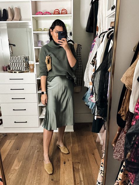 Short haired brunette woman wearing an oversized cowl neck sweater in dark green with a coordinating satin skirt in a lighter sage green hue, standing in a closet taking a selfie. Green Slip Skirt Outfit, Slip Skirt Outfit Spring, Sweater Skirt Outfit Winter, Slip Dress With Sweater, Graphic Sweater Outfit, Skirt With Sweater Outfit, Satin Skirt Outfit Classy, Slip Skirt Outfit, Silk Slip Skirt