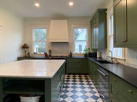 Green custom cabinetry, black and white checkerboard tiles, a large island with marble countertop, and original windows make this kitchen timeless. Green Kitchen Cabinets Black And White Floor, Green Cabinets Black And White Floor, Green Kitchen Black And White Floor, Black Green White Kitchen, Check Kitchen Floor, Green Kitchen Cabinets Tile Floor, Green Black And White Kitchen, Black And White Checkered Floor Kitchen Green Cabinets, Checkered Floor Green Cabinets