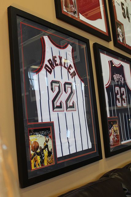 Decorative solutions by simply framing sports memorabilia, such as these vintage Houston Rockets jerseys. #nba #dexler #pippen | Houston TX | Gallery Furniture | Frame Jersey Ideas, Sports Memorabilia Display, Sports Man Cave, Clyde Drexler, Cheap Living Room Sets, Memorabilia Display, Jersey Display, Frame By Frame, Framed Jersey