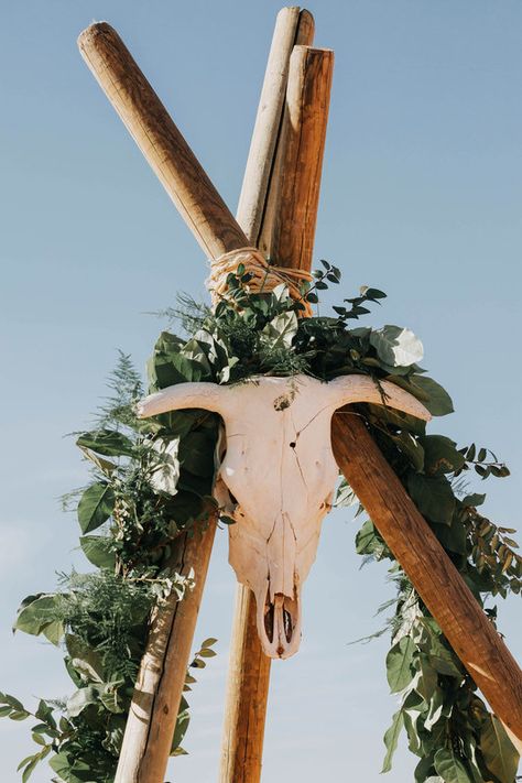 A sun-bleached cow skull and luscious garlands of greenery adorn the top of this wedding arch at this wild, boho, desert wedding. The Sea Background, Boho Desert Wedding, Crop Top Wedding Dress, Outdoor Backdrops, Sea Background, Seaside Theme, Boho Desert, Boho Beach Wedding, Skull Wedding