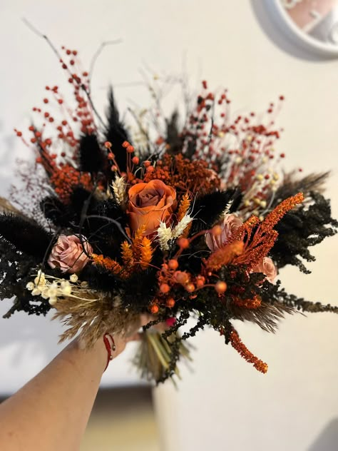 Introducing the stunning Black and Orange Gothic Wedding Bouquet, featuring a mesmerizing Rose Bridal Bouquet infused with enchanting autumn vibes. This one-of-a-kind arrangement showcases dried flowers, adding a distinctive touch to your special day. Perfect for a unique Halloween wedding, this bouquet measures 40cm in width and 45cm in height, making it a captivating centerpiece. Elevate your wedding with this exquisite bouquet that effortlessly combines elegance, Gothic aesthetics, and the spirit of the season. Pumpkin Wedding Bouquet, Halloween Wedding Flowers Bridal Bouquets, Black And Orange Boho Wedding, Dried Flower Bouquet Wedding Autumn, Harry Potter Inspired Bouquet, Gothic Wedding Flower Arrangements, Autumn Dried Wedding Flowers, Halloween Flower Centerpieces, Purple Black And Orange Bridal Boutique