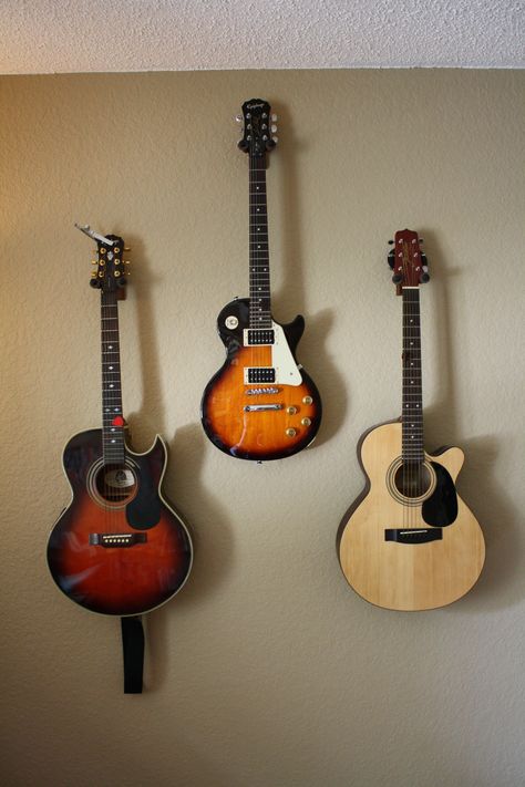 Guitars hung on the wall with mounts. Mount Guitars On Wall, Guitars Hung On Wall, 2 Guitars On Wall, Guitar Hanging On Wall, Guitar Hanging Ideas Wall Mount, Guitar Hanging Ideas, Guitars Hanging On Wall, Guitar Hangers Wall, Guitar Wall