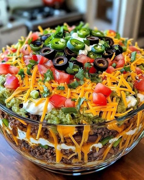 🌮🥗Seven-Layer Taco 🥗 🌮 Ingredients: 1 can of refried beans/ Ground Beef 1 cup sour cream 1 cup salsa 1 cup shredded cheddar cheese 1 cup shredded lettuce 1/2 cup diced tomatoes 1/2 cup sliced black olives 1/4 cup chopped green onions 1/2 tsp ground cumin 1/2 tsp garlic powder Salt and black pepper to taste Tortilla chips (for serving) Directions: Prepare the Layers: In a small bowl, mix the sour cream with ground cumin, garlic powder, salt, and black pepper. Assemble the Salad: Spread t... Layer Taco Salad, Layered Taco Salads, Taco Salad Ingredients, Seasoned Sour Cream, Layered Taco Dip, Seven Layer Dip, Taco Salads, Taco Salad Recipes, Layered Salad