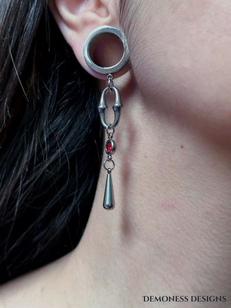 **No stretched lobes? No problem! We also offer earring options, so you can rock this look even without stretched ears! ** Elevate your style with these bold, alternative ear tunnels. Featuring a statement chain link, a striking red gem connector, and a sleek pendulum charm, these tunnels embody the perfect blend of edgy and gothic aesthetics. Crafted for those who seek a distinctive, powerful look, they bring a unique fusion of strength and elegance to your ensemble. ✨Features ✨ ✧ Sizes 6mm to 30mm - A wide range of sizes to fit most ears ✧ Handmade to order - Each piece is crafted with care, ensuring quality and uniqueness. ✧ Made to last - Made of 100% stainless steel, waterproof and tarnish resistant, perfect for daily wear ✧ Sold as pairs - All ear tunnels are sold as pairs, ensuring Gothic Mode, Measurement Conversions, Stretched Lobes, Ear Tunnels, Gothic Design, Gauged Earrings, Plugs Earrings, Stretched Ears, Red Accents