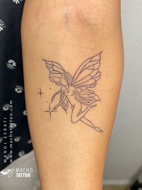 A photo of a tattoo on someone’s arm. The tattoo is of a fairy with wings and a dress. The tattoo is done in black ink and is in an outline style. The tattoo is located on the upper arm near the shoulder. The background is a black and white floral pattern. There is a watermark on the image that reads “MACHO TATTOO www.machotattoo.com”. The tattoo was done by Macho Tattoo, a professional tattoo studio in Hyderabad that offers a wide range of services and styles. Geometric Lion Tattoo, Tattoo Black And White, Black And White Outline, Lipstick Tattoos, Tiny Wrist Tattoos, Becoming A Tattoo Artist, Unicorn Tattoos, Fairy Tattoo Designs, Moon Tattoo Designs