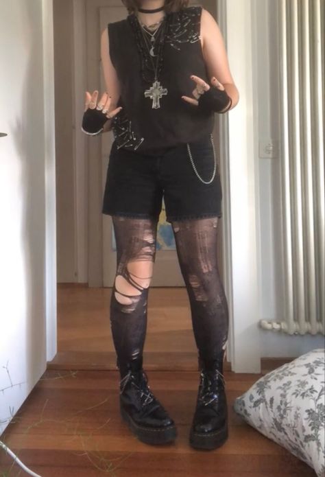 A mid-sized person/girl wearing a brown safety pin sweater vest with black shorts and patterned flower tights underneath, black fingerless gloves, black platform dr. Martens and multiple crystal rings and bracelets. 		The person is also wearing multiple silver necklaces. Dark Neutral Clothes, Summer Goth Masc, Goth Outfits Nonbinary, Dark Punk Outfits, Masc Goth Outfits Summer, Cute Masculine Outfits, Punk Outfit Inspiration, Grunge Androgynous Outfit, Alt Outfits With Shorts