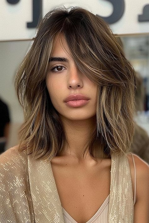 A woman with a textured long bob and side-swept bangs, showcasing choppy layers and balayage tones. Lob With Face Framing Layers Side Part, Textured Long Bob With Bangs, Long Bob With Side Swept Bangs, Bob Haircuts With Side Bangs, Lob For Thick Hair, Haircuts With Side Bangs, Bob With Side Swept Bangs, Layered Long Bob, Cut Side Bangs