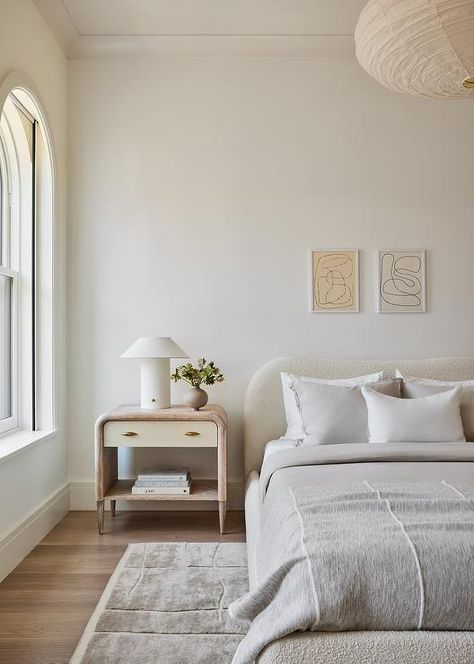 Modern bedroom features abstract art over an ivory boucle headboard with light gray bedding, a curved oak nightstand lit by a white lamp and a light gray rug. Restful Bedrooms, Grey Headboard, Custom Furniture Design, Bedroom Headboard, Guest Bedrooms, New Room, Bedroom Makeover, Modern Bedroom, Bedroom Inspirations