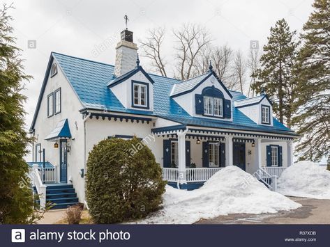 Download this stock image: Old 1920s white roughcast with blue trim cottage style home facade with blue steel tile roof in early spring, Quebec, Canada - R37XDB from Alamy's library of millions of high resolution stock photos, illustrations and vectors. White House With Blue Roof, Blue Metal Roof Houses Color Combos, Metal Roof Houses Color Combos, Blue Roof House, House With Blue Roof, Home Facade, Metal Roof Houses, Steel Tiles, Irish Houses