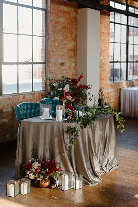 Sweetheart table inspo: bridal bouquet with black framed lanterns were the perfect addition to the trailing greens and bud vases atop the charcoal velvet cloth. Obsessed with these teal chairs, the perfect compliment for this jewel toned wedding at Tenth Ward Distillery Bridal Bouquet With Black, Jewel Tone Wedding Decor, Jewel Tone Wedding Invitations, Jewel Toned Wedding, Wedding Design Inspiration, Sweetheart Table Wedding, Jewel Tone Wedding, Wedding Tablecloths, Velvet Cloth