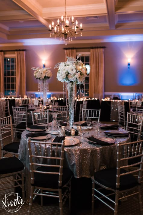 Black Floor Length Table Cloths with a Silver Sequin Overlay, Silver Charger Plate & Pleated Black Napkin Silver Sequin Tablecloth, Black And Silver Banquet Decorations, Black And Silver Reception Decor, Black And Silver Masquerade Party, Silver Debut Theme, Black And Silver Wedding Reception, Black White And Silver Quince, Black White And Silver Wedding Reception, Silver Quince Decorations