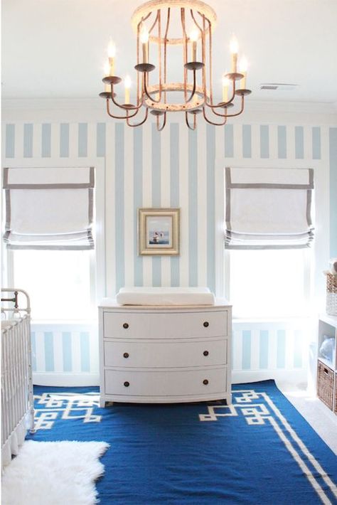 White and blue boy's nursery features blue and white striped wallpaper framing windows dressed in white roman shades with gray grosgrain trim flanking Ingrid Chest doubling as a changing table atop blue Greek key rug, Surya Alameda Rug, Illuminated by Gabby Home Adele Chandelier. Baby Nursery Wallpaper, Girl Nursery Wallpaper, Grey Nursery Boy, Striped Nursery, Blue Nursery Boy, Blue Dresser, Closet Room, White Nursery