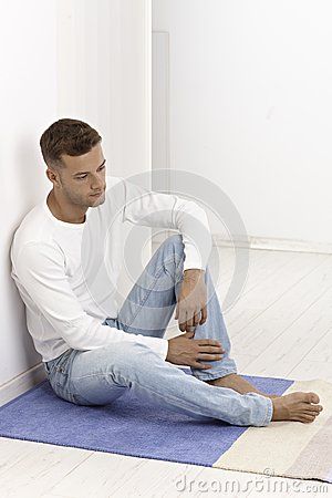 Young man sitting on floor looking sad by Nyul, via Dreamstime Drawing Reference Poses Sitting On Floor, Siting On Floor Pose Reference, Siting Pose References Floor, Person Sitting Against Wall, Man Sitting Reference, Person Sitting On Floor Reference, Cross Legged Pose Drawing, Person Sitting On Floor, Sitting On The Floor Pose