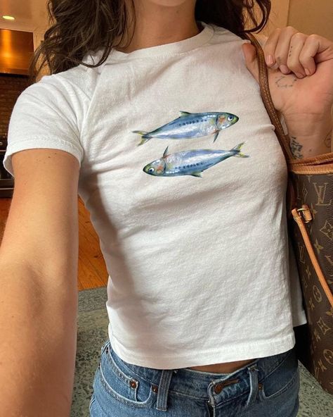 Dive into the nostalgic vibes of the 90s and Y2K era with our "Sardines Baby Tee Coquette Shirt." This slim-fit, mid-length baby tee is designed to hug your curves, offering a flattering silhouette that's perfect for the "Oceancore" aesthetic. Made from 100% organic cotton rib, it combines comfort with sustainability, making it an ideal choice for everyday wear, whether you're embracing the "Seafood Teenage Girl Clothing" trend or simply looking to elevate your summer wardrobe. Quick Facts Material: 100% organic cotton rib for a soft and eco-friendly feel Care Instructions: Machine wash cold, tumble dry low for best results Sizing Fit: Slim fit, designed to highlight your figure Length: Mid-length cut for a stylish look Shipping Times Processing: Each tee is crafted with care just for you. Fish Shirt, Baby Tee, Baby T Shirts, Fishing Shirts, Summer Baby, Infant Tees, Summer Wardrobe, 90s Fashion, Organic Cotton