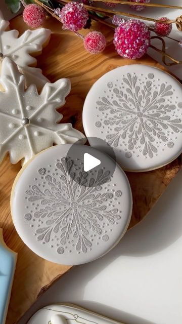 Annamaria Valentino || Mary on Instagram: "A glittery snowflake made simple using a stencil and edible sparkle dust 💫💫 make sure your royal icing base is completely dry before stenciling. Use a medium to stiff consistency icing to scrape across the stencil, then finish with some edible sparkle dust and lift the holder to reveal a perfect snowflake ❄️ You can find all of these tools/supplies on my website 💫💫💫💫. I will list them all below : ❄️Pretty snowflake stencil 🖤Super Black Fondust (used a touch of Colourant for this grey colour) 💫Nu Silver edible sparkle dust ❄️The sweet stencil holder- an amazing tool that gives THE PERFECT stenciling every single time! Comment below and follow for more ! 💫 #emmassweets #cookiedecorating #cookoedecoratingvideo #cookiedecoratingsupplies #cook Stenciled Cookies Royal Icing, Royal Icing Stencils, Stencil Cookies Royal Icing, Royal Icing Tools, Elegant Birthday Cookies Decorated, Snowflake Decorated Sugar Cookies, Snow Globe Christmas Cookies, Silver Royal Icing, Christmas Sugar Cookies Decorated Ideas