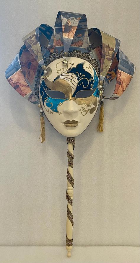 This Authentic Venetian full face mask features a hand-painted design in shades of blue, perfect for Mardi Gras or Carnival masquerade events. The mask follows a Venetian theme with intricate detailing, made of paper material. Ideal for those looking for a unique and stylish accessory for a masquerade ball or costume event. Multicolored cream with blue, black and gold hand painted detailing on face. Decorative paper spirals printed on them tipped with jingle bells at the ends. A Wood Handle Venetian Mask in papier mache with a lovely silk gold ribbon wrapped from down the handle. Authentically handcrafted according to the original Venice carnival tradition. Manufactured in Venice by the famous venetian masters. Stamp of authenticity on interior of mask. Great for any collectors or home dec Paper Mache Masquerade Mask, Jester Mask Design, Paper Mache Mask Ideas, Medieval Mask, Carnaval Mask, Veil Mask, Carnivale Mask, Venetian Costumes, Carnival Masquerade