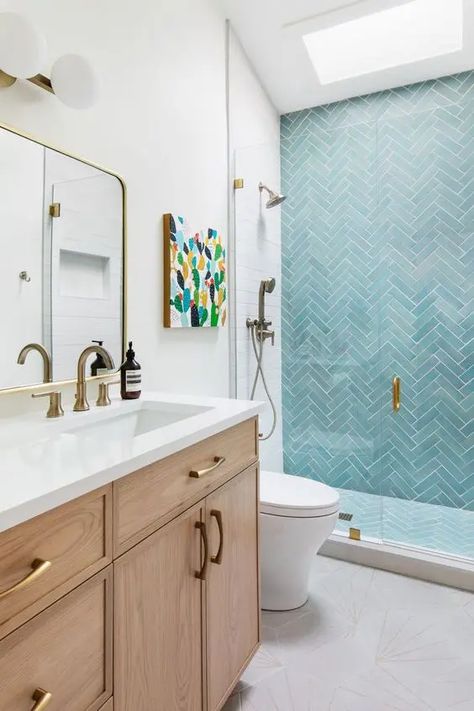 Picture of a cool modern bathroom with a skylight, a shower space with turquoise herringbone tiles, a stained vanity and brass fixtures Bathroom With Light Blue Tile, Herringbone Shower Tile Accent Wall, Blue White Bathroom Tile, Blue And Oak Bathroom, Bathroom Blue Tile Wall, Blue Accent Tile Shower Wall, Bathroom Herringbone Tile Wall, White Bathroom With Blue Accents, Light Blue Tile Bathroom