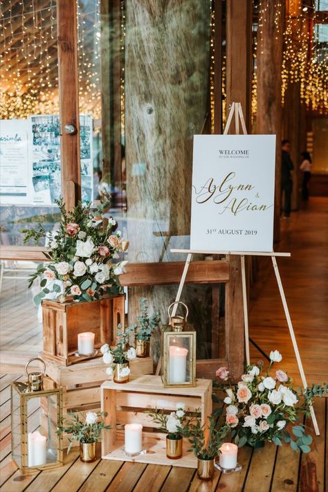 A wedding clad in gold. This wedding theme surely gives off a more warm and rustic feel. Decorated with fresh flower arrangements of white and pink roses at the entrance, tables and wedding arch. Plus, a viking table seating set up with pillar candles, foliage lining and cutleries on the table, with gold chiavari chairs. Wedding Decorations With Candles, Wedding Entrance Table, Viking Table, Entrance Tables, Wedding Welcome Table, Fresh Flower Arrangements, Reception Entrance, Wedding Entrance Decor, White And Pink Roses