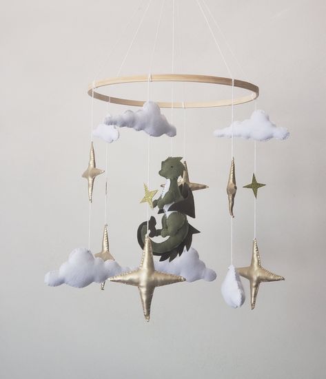 Baby mobile with dragon is perfect decoration for a baby girl or boy nursery room. This mobile its a one of a kind final touch to your new little one.Simply,delicate decoration for nursery. Mobile includes  6 gold stars  6 white clouds Green dragon  Diameter of the hoop 10 inches Crib arm attachment  is not included! Fairy Forest Nursery Theme, Elven Themed Nursery, Dragon Mobile Baby, Dragon Nursery Boy, Dnd Nursery Theme, Fairy Tale Nursery Theme, Dragon Baby Nursery, Magical Forest Nursery, Dragon Themed Nursery