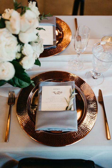 Elegant copper wedding place setting with a dusty blue napkin, copper silverware & a white wedding flower arrangement  | Planned & Designed by Dallas Fort Worth Wedding Planners Shannon Rose Events | Photographed by Wilderlove Co. | Be sure to click the link below for more wedding ideas & inspiration! Navy Sage And Copper Wedding, Copper And Green Wedding Theme, Copper Centerpieces, Wedding Copper, Copper And White Wedding, Navy Copper Sage Wedding, Spring Copper Wedding, Wedding Table Setting Ideas Round, Dusty Blue And Copper Wedding Theme