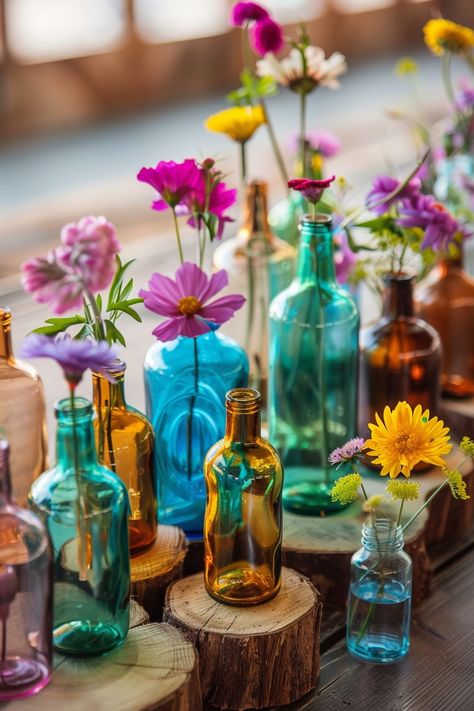 Capture the essence of bohemian elegance on your special day 🌸. These simple yet stunning wedding table centerpieces combine rustic wood slices and vibrant glass bottles for a unique touch. Perfect for couples who love a pop of color and natural beauty in their decor. #BohoWedding #WeddingInspiration #CenterpieceIdeas #WeddingDecor #DIYWedding #RusticChic #FloralDecor #WeddingDetails Simple Boho Wedding Decor, Wildflower Wedding Table Decor, Bohemian Wedding Table Decor, Driftwood Wedding Centerpieces, Unique Table Centerpieces, Jar Centerpiece Wedding, Colorful Table Decor, Driftwood Wedding, Boho Cowboy