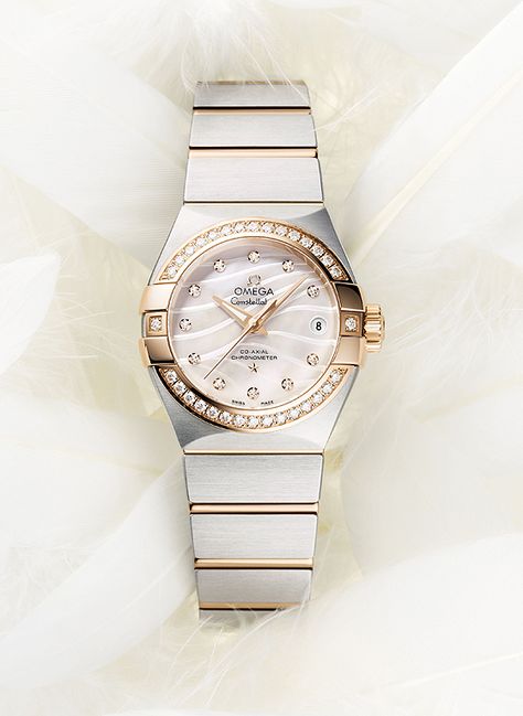 The Omega Constellation Pluma has a mother-of-pearl dial, in natural white or blue, which features an engraved, wavy pattern that recalls the shapes of a feather (“Pluma” is Latin for “feather”). The white-dialed model has a bezel in 18k rose gold and 18k rose gold links in the steel bracelet. Omega Watch Women, Swiss Army Watches, Armani Watches, Omega Constellation, Vintage Omega, Vintage Watches For Men, Womens Watches Luxury, Stylish Watches, Fine Watches