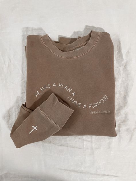 This 'He Has a Plan and I Have a Purpose' embroidered sweatshirt is embroidered in a wave and features 'Jeremiah 29:11' below it. It's the perfect Christian sweatshirt to wear for Easter, on Sundays, or any day. You'll find yourself reaching for it because it's SO cozy and it even passes the aesthetic vibe with the vintage pigment-dyed look. Example photo pictured on pigment clay with ivory thread and the cross upgrade for the wrist. Standard unisex sizing. For women, ordering your normal size will be relaxed and sit at the hips. For an oversized look, size up one (or two if you like really oversized). Sweatshirt Inspo Aesthetic, Clothing Brand Pictures, Cute Christian T Shirts, Christian Tops For Women, Simple Crewneck Design, Cute Christian Clothes, Aesthetic Merch Ideas, Trendy Clothes For Women Casual, Christian Clothes Aesthetic