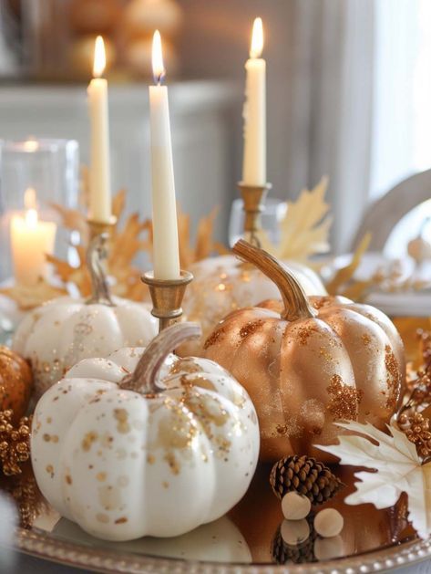 For a sophisticated and festive centerpiece, look no further than this glittering pumpkin arrangement. Gold and white pumpkins, dusted with sparkling accents, are beautifully complemented by tall, slender candles. The warm glow of the candles reflects off the shimmering pumpkins, creating a luxurious and inviting atmosphere. This centerpiece is perfect for an elegant fall dinner party, adding a touch of glamour and enchantment to your table decor. White And Gold Pumpkins, Modern Thanksgiving Tablescapes, Fall Bridal Shower Ideas, Glam Fall Decor, Fall Candle Centerpieces, White Pumpkin Centerpieces, Pumpkin Tablescape, Pumpkin Table Decorations, Ideas For Autumn