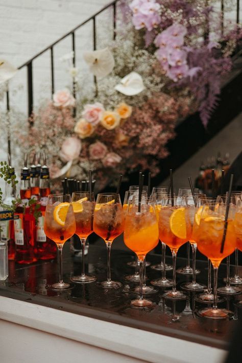 Rows of Aperol Spritz for the wedding cocktail hour Aperol Spritz Wedding, Wedding Drink Ideas, Flower Columns, Wedding Cocktail Hour Food, Cocktail Engagement Party, Cocktails Wedding, Drinks Wedding, Handfasting Ceremony, Wedding Cocktail Hour