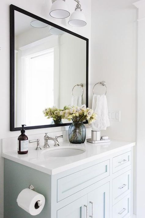 Lit by a white two light sconce, a pale blue vanity painted Benjamin Moore Woodlawn Blue is accented with a white quartz countertop holding a round sink with a polished nickel faucet kit beneath a black mirror mounted on a white wall beside a polished nickel towel ring. Blue Cabinet, Tiled Shower, Gorgeous Bathroom, White Vanity Bathroom, Perfect Blue, Trendy Bathroom, Girls Bathroom, Bathroom Storage Cabinet, Studio Mcgee