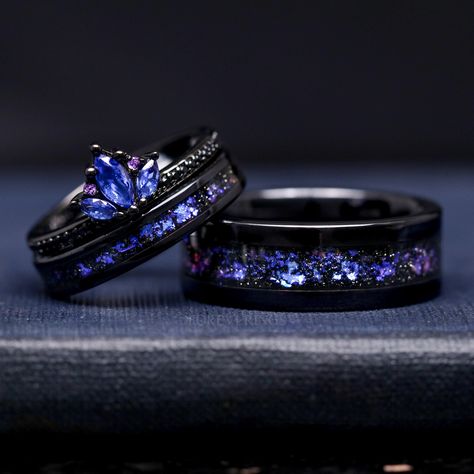 When a blue lotus meets Orion Nebula, magic happens. The Blue Lotus Orion Nebula Couples Ring Set captures the essence of the cosmos with its stunning blue nebula pattern. This unique design is the perfect choice for those couples seeking a personalized, celestial-inspired promise, engagement, or wedding ring set. ►Sold as a three-piece set Engagement Ring: ►Material: Sterling Silver with Black Rhodium Plating ►Center Stone: Sapphire ►Side Stone: Amethyst and Black Diamond (CZ)  Wedding Bands: ►Material: Ceramic ►Inlay: Crushed Sandstone ►His Band Width: 8mm ►Her Band Width: 4mm ►Fit is true to size ►Your nebula inlay is protected with a coating that defends it from water, dirt, and grime. ►Ceramic rings are a very durable wedding ring option. Ceramic rings are made from jewelry-grade cera Black And Blue Wedding Ring, Engagement Rings For Men Black, Purple Ring Wedding, Wedding Rings Sets His And Hers Silver Matching Couples, Silver Wedding Rings Unique, Hers And Hers Wedding Rings, Space Themed Wedding Rings, Acotar Wedding Ring, Celestial Wedding Rings