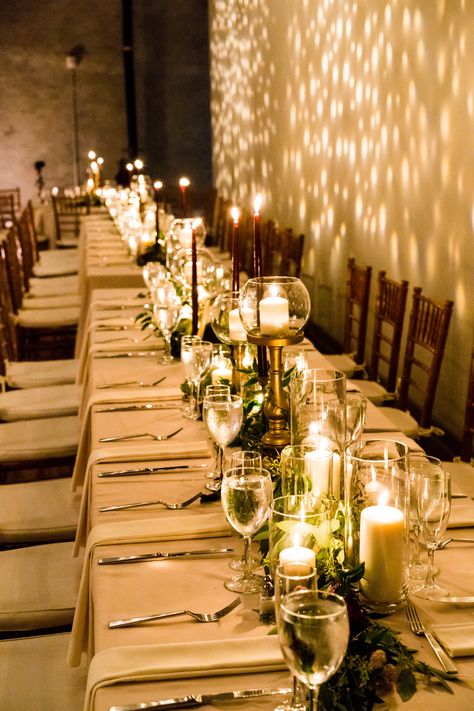 Long table simple greenery and candle centerpieces for an autumn wedding designed and created by Wild Stems at Front & Palmer in Philadelphia, PA. Venue is Front & Palmer. Catering by Feast Your Eyes. Lighting by Synergetic Sound, Inc. Photo by Stephen Govel Photography. #weddingflorist #floraldesign #weddingcenterpiece #weddingflowers #philadelphiaweddings #philadelphiafallwedding Long Tables Wedding Reception Candles, Feast Table Wedding, Long Wedding Table Decorations Candles, Candles For Centerpieces Wedding, Pilar Candle Centerpiece, Wedding Table Decor For Long Tables, Floating And Taper Candles Wedding, Lots Of Candles Centerpiece, Low Long Centerpieces Wedding