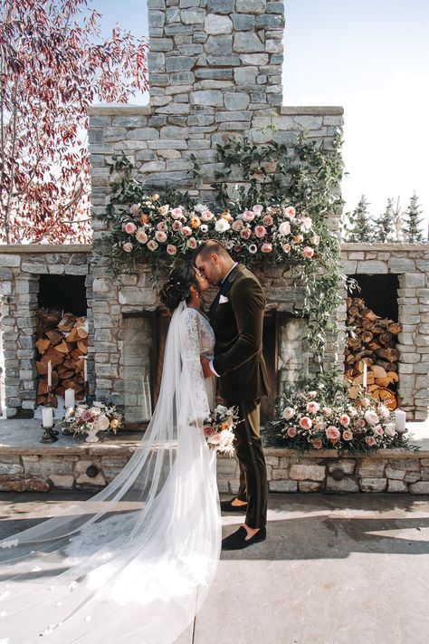 This outdoor natural fireplace at Flores and Pine wedding venue in Calgary, Alberta is the perfect backdrop for your wedding ceremony, couples portraits and guest photos. Photo: 20.20 Photography  #outdoorpatio #outdoorwedding #fireplaceflowers #weddingfireplace #mantelflowers #calgaryweddingvenues #calgarywedding #floresandpine #calgaryflorist #flowersbyjanie #calgaryweddingflowers #calgaryweddingflorist #outdoorpatiowedding #stonefireplace Wedding Outdoor Fireplace, Outdoor Fireplace Wedding Ceremony, Medium Sized Wedding, Fireplace Wedding Ceremony, Outdoor Patio Wedding, Natural Fireplace, Calgary Wedding Venues, Creek Ideas, Pine Wedding