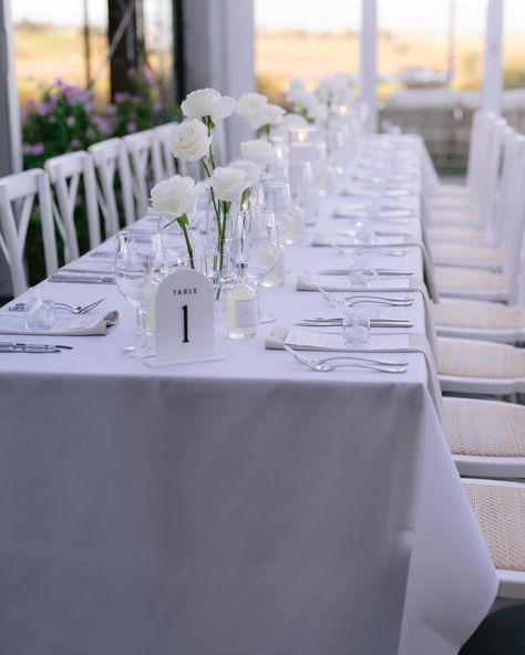 🌿✨ Timeless Beauty ✨🌿 White Ecuador rose stems in bud vases paired with the warm glow of candles. Simplicity at its finest. @vinesoftheyarravalley #WhiteRoses #MinimalistDecor #CandleLight #ElegantSimplicity #TimelessBeauty #weddingfloralsmelbourne #weddingflowersmelbourne #weddingbouquet #weddingfloristmelbourne #melbourneweddingflorist #weddingflowers #weddingflorist #bridalbouquet #melbournewedding Single Bud Vases Wedding, White Rose Bud Vase Centerpiece, Single Stem Centerpiece With Candles, Single Flower Bud Vase, Bud Case And Candle Centerpiece, White Rose Bud Vase, Single Stem Centerpiece, White Rose Wedding Table, Bud Vases Wedding Centerpiece